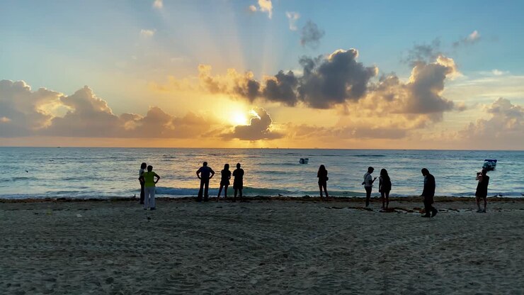 Silhouette Of People Watching Sunrise On Playa Del Carmen Beach In Mexico - wide shot