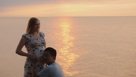marido feliz presiona la oreja contra el vientre de su esposa embarazada