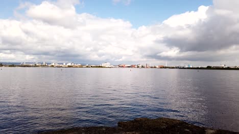 Tiro-Panorámico-De-Lapso-De-Tiempo-Del-Canal-De-Bristol-Tranquilo-Y-La-Ciudad-De-Cardiff-En-Segundo-Plano