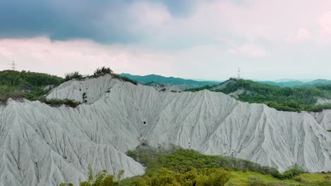 aerial approaching shot of granitic mountains named moon world tianliao, taiwan during cloudy day, 田寮月世界, tiánliáo yuè shìji?