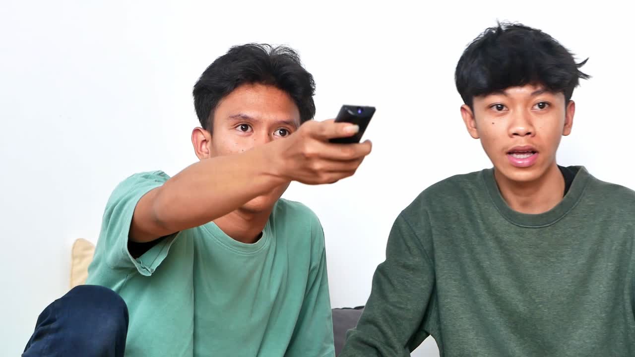 Relaxed friends enjoying leisure time watching entertainment with remote control fun at home