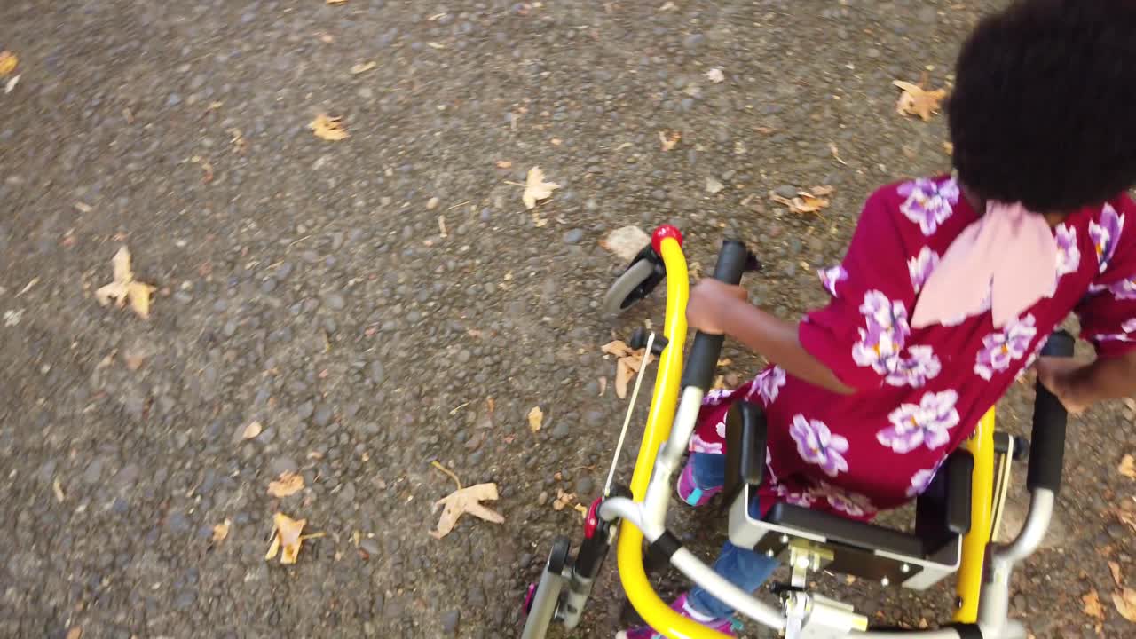 niña negra con parálisis cerebral caminando en el parque con su dispositivo de asistencia