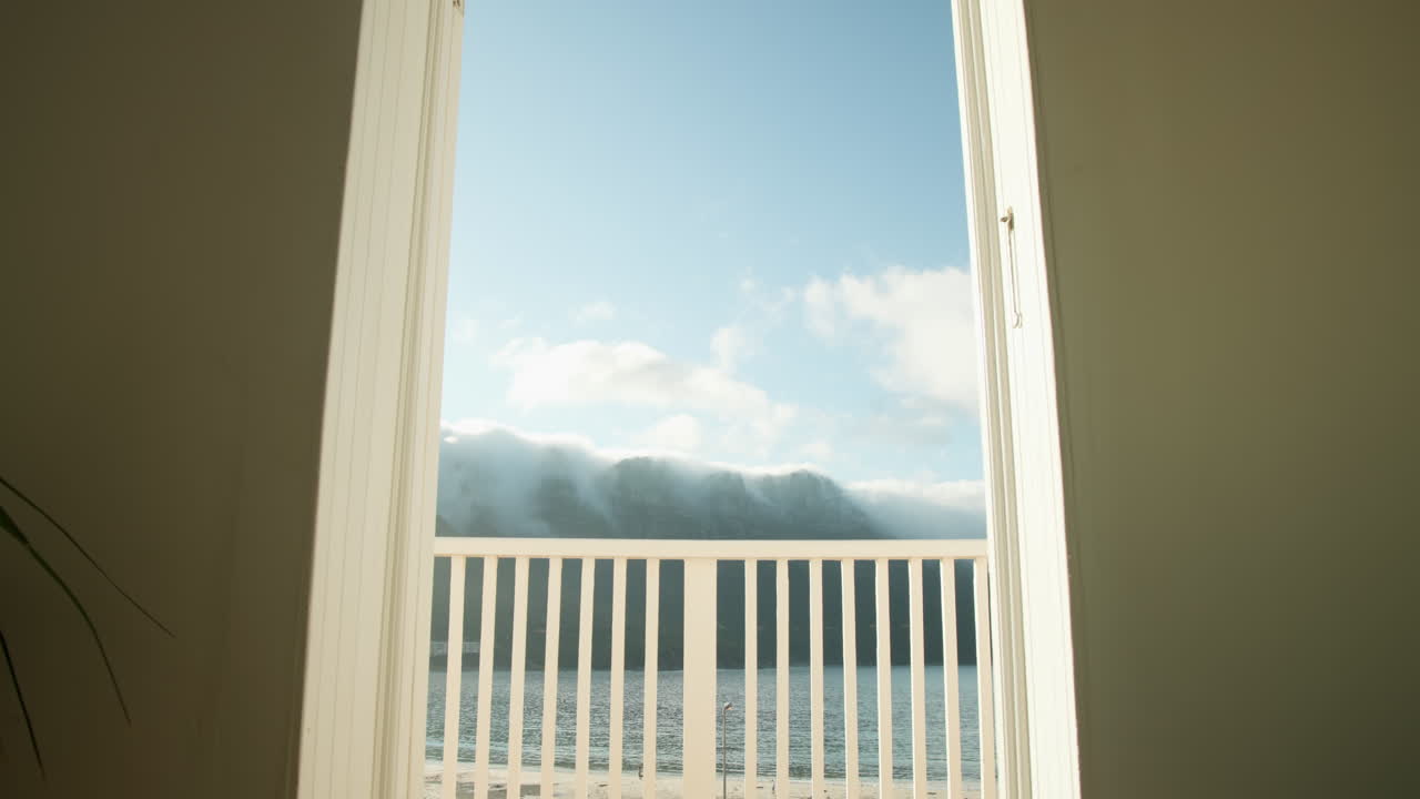 Open balcony door revealing serene ocean view with clear blue sky, copy space