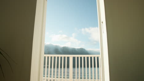 open balcony door revealing serene ocean view with clear blue sky, copy space