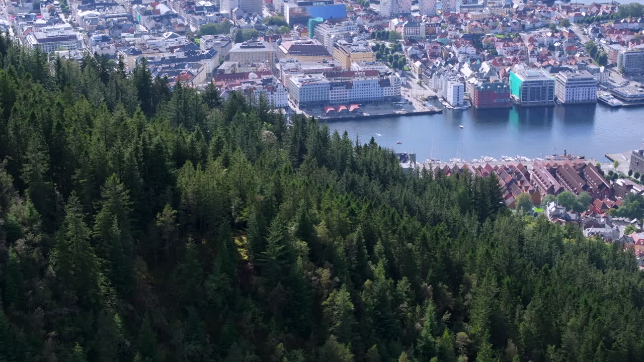 Drone tracking shot moving sideways along Fløyen mountain, gradually revealing Bergen’s skyline and waterfront
