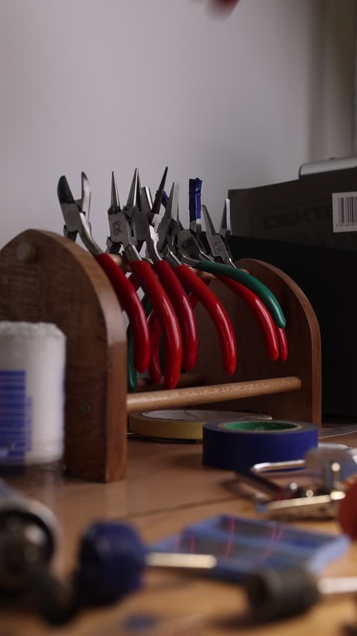 Hand Picking Up Pliers from a Wooden Tool Holder on a Workbench