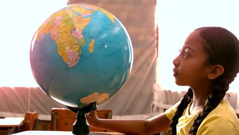 Little-girl-looking-at-globe-in-classroom
