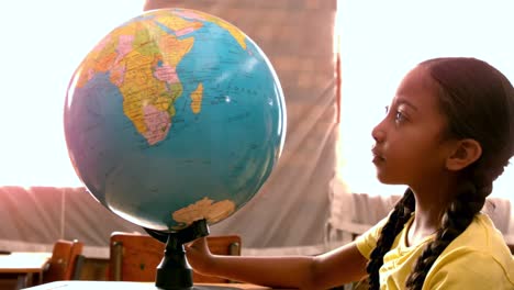 little girl looking at globe in classroom