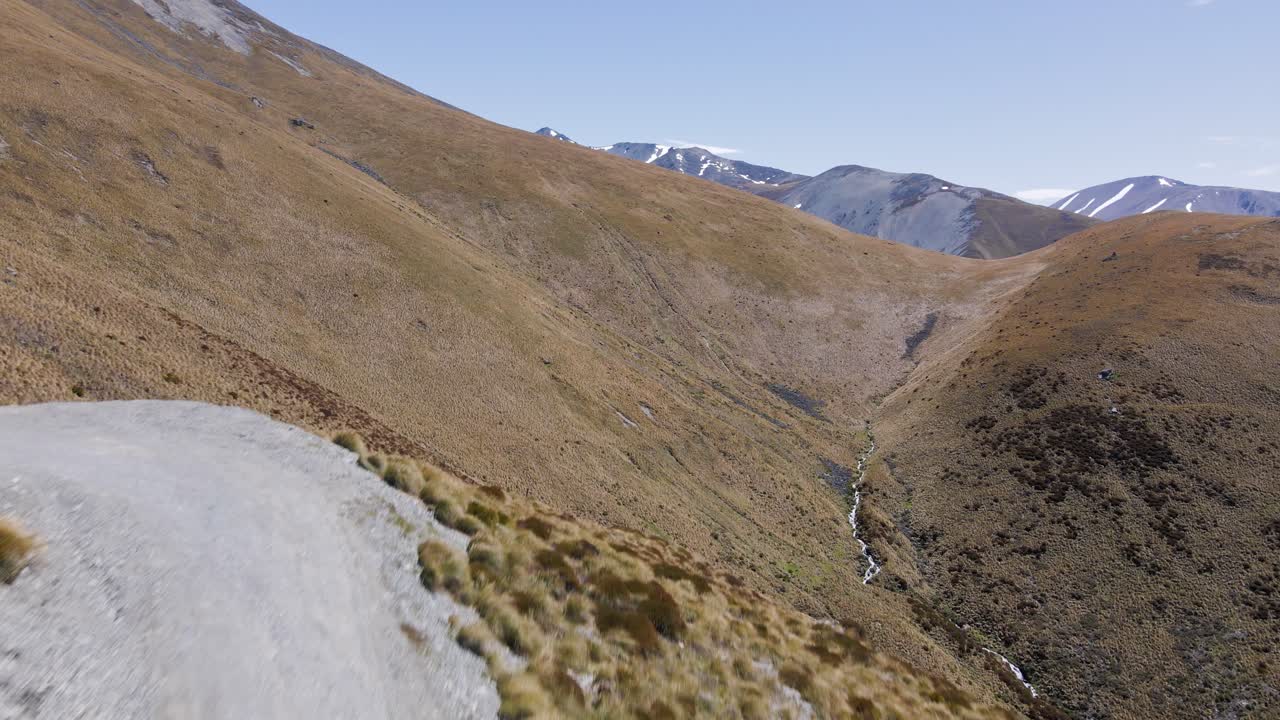 tres hombres caminando por una empinada y polvorienta carretera de montaña en mackenzie, nueva zelanda