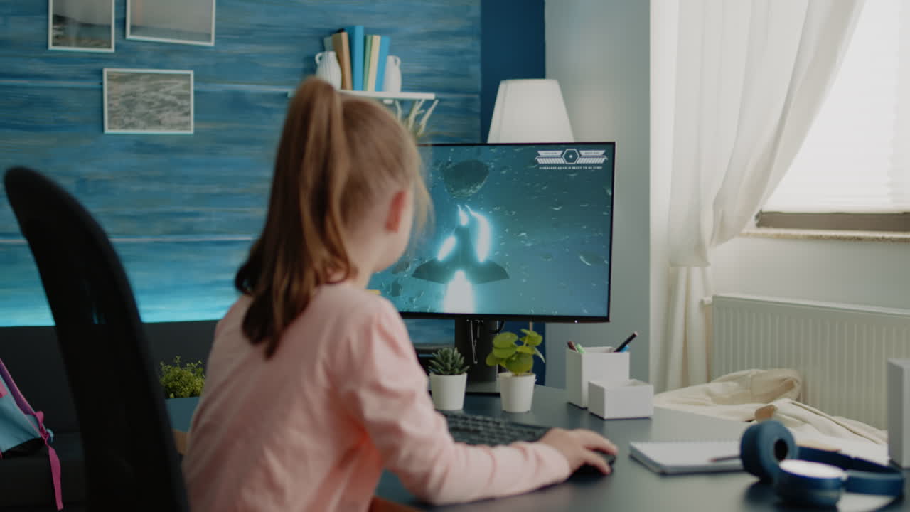 Young girl playing shoot video games on computer at desk