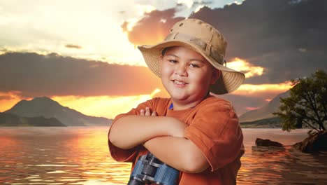 niño asiático con un sombrero y binoculares cruzando los brazos y sonriendo a la cámara en un lago. niño investigador examina algo, aventura de viaje, vista lateral de cerca