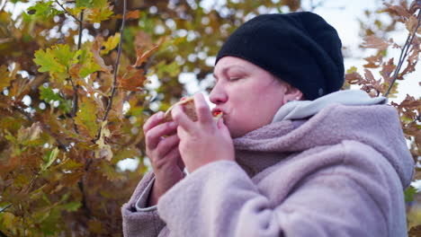 mujeres comiendo comida afuera junto a un árbol cubierto de hojas coloridas mientras acampan