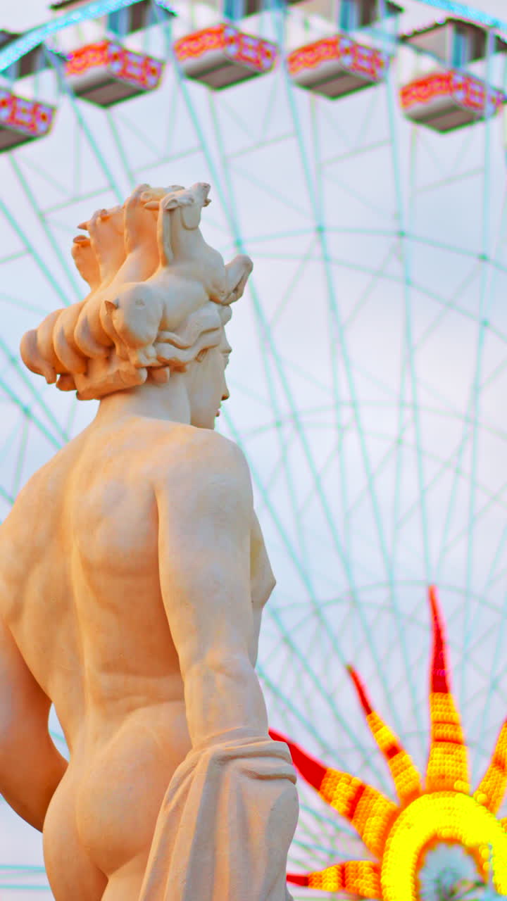 Nice, France - December 8, 2024: Apollo statue in the Fontaine du Soleil at Place Massena with a ferris wheel on the background. Vertical