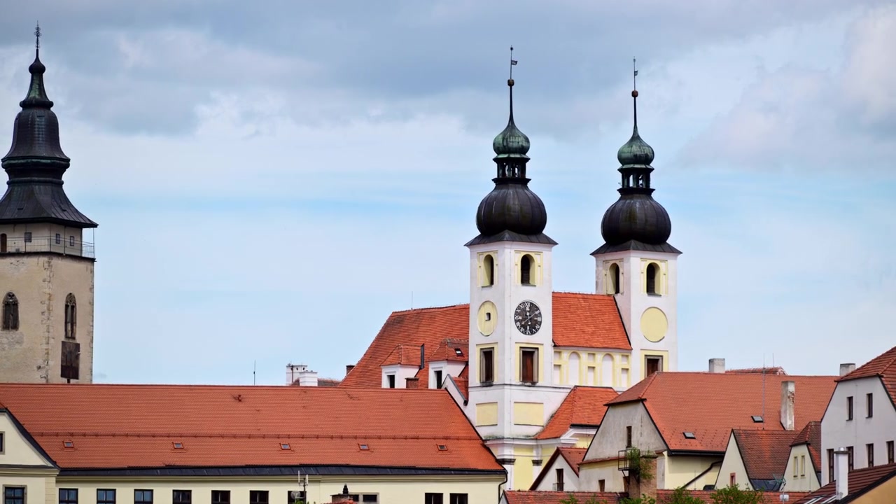 Vista di un campanile in pietra e torri gemelle di chiese barocche con cupole a cipolla sopra tetti rossi, Telč, Repubblica Ceca