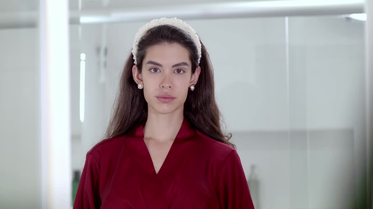 La modella sorride con grazia, i suoi occhi si illuminano e saluta con fascino radioso.
