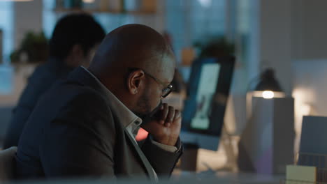 african american businessman working late in offce using computer brainstorming browsing online research planning deadline for corporate project