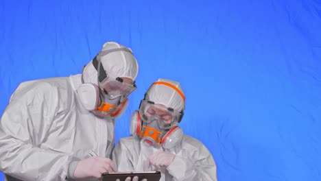 scientist virologist in respirator makes write in an tablet computer with stylus. man and woman wearing protective medical mask. chroma key blue.