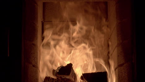 dolly shot across the inside of a log burning fireplace with high flames, bright golden orange flames