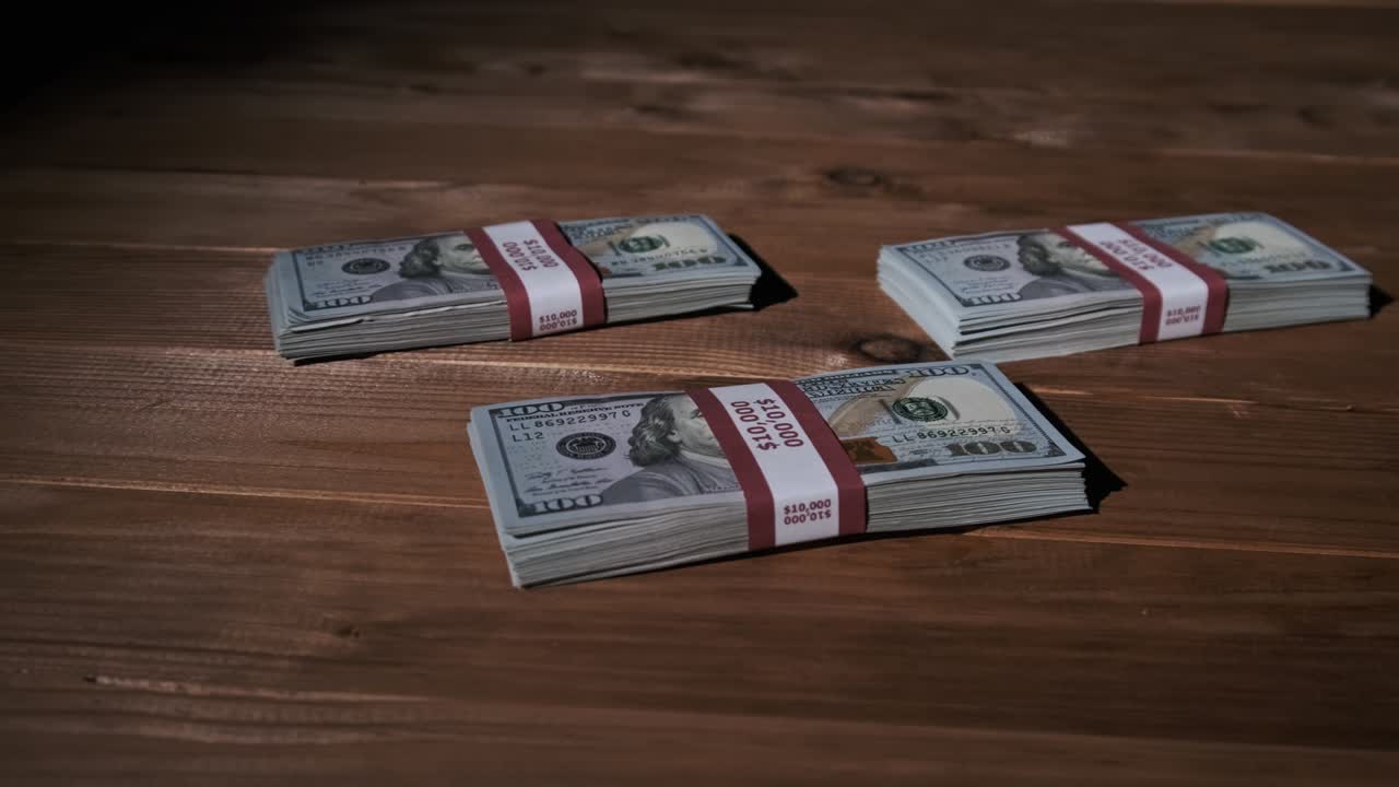 Three Stacks of 10000 American Dollars Banknotes in Bundles Lie on Wooden Table