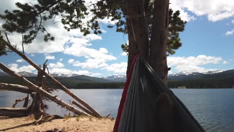 vista desde una hamaca meciéndose en el viento por un embalse con montañas cubiertas de nieve en el fondo en un día de verano en wyoming