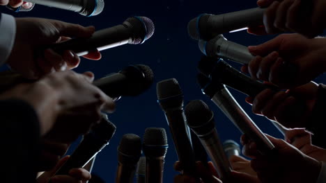 many hands holding microphones at a press conference or media event