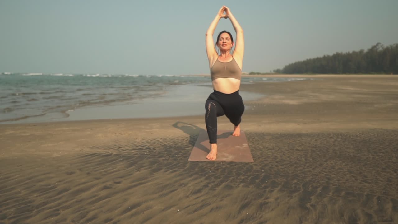 Donna facendo esercizi di yoga sulla spiaggia