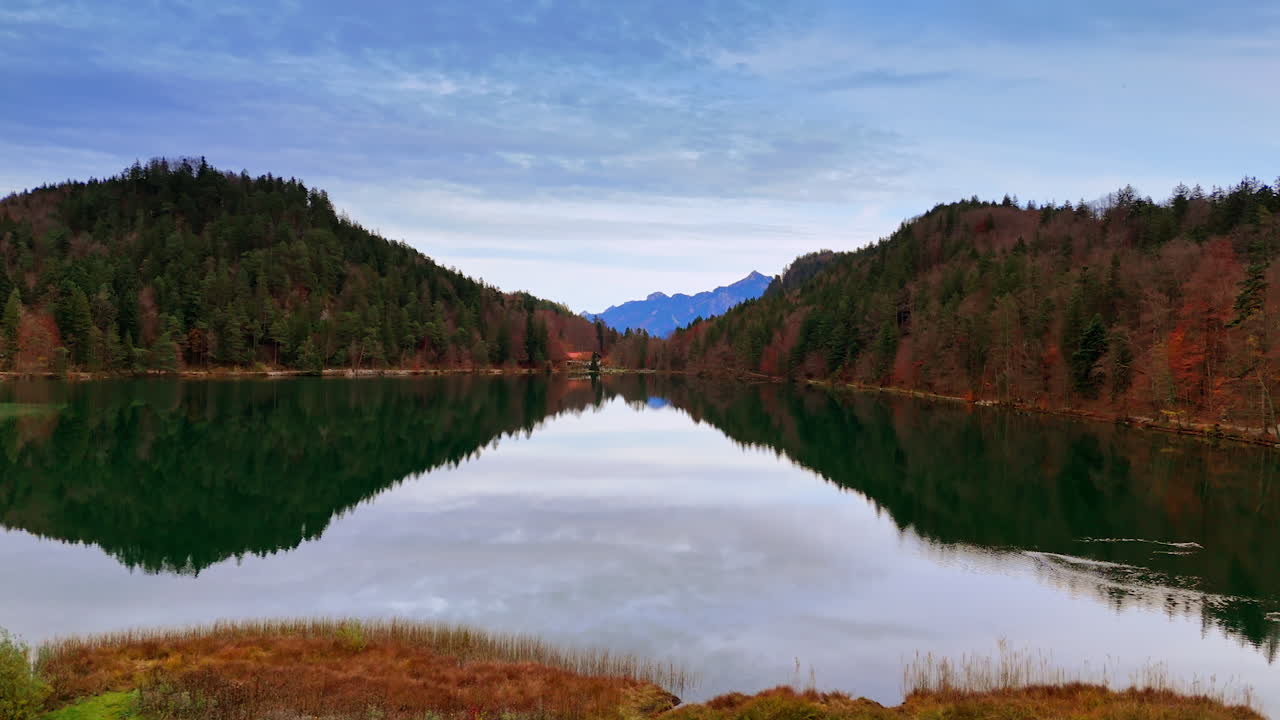 Mountain lake between forests. A calm alpine lake in Bavaria surrounded by forested hills and peaks
