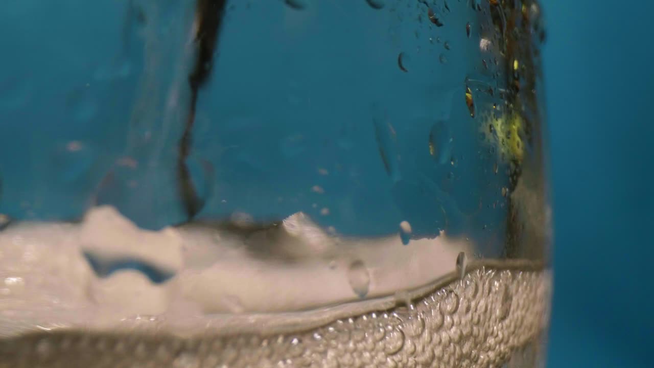 burbujas de primer plano en un vaso con un fondo azul. foto de paquete en cámara lenta