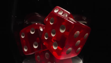 red dices with white dots thrown into transparent glass