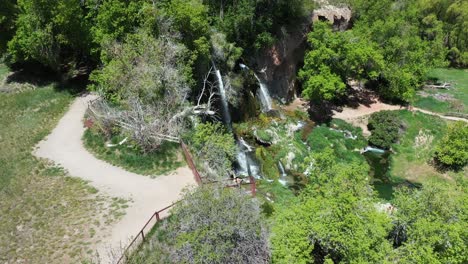 vista aérea, mujer mirando por encima de las cataratas del rifle en un día soleado de verano, cascadas y paisaje verde del parque estatal de colorado, disparo de drones