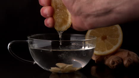 Hand-squeezing-lemon-into-cup-of-hot-water-and-ginger