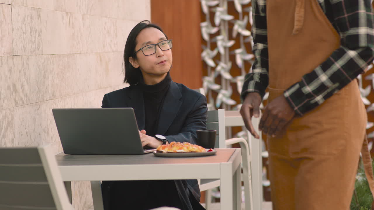 랩톱 컴퓨터에서 작업하고 커피숍에서 점심을 먹는 동안 웨이터에게 무언가를 주문하는 사업가