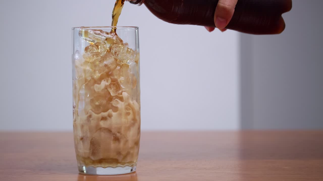 A hand pours a cool drink over ice showcasing a refreshing moment a modern kitchen