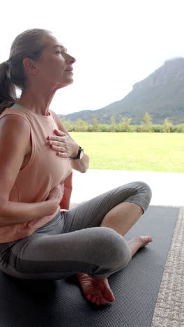 vertical video: practicing mindfulness, woman sitting cross-legged on yoga mat outside