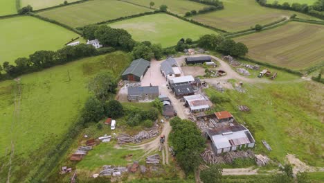 Aerial-view-of-a-smallholding-lumber-yard-with-various-buildings-and-wood-piles-in-a-rural-setting