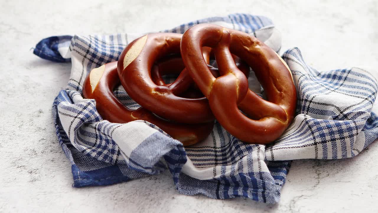 Kolme saksalaista tuoretta paistettua pretzeli-sämpylää aseteltuna lautasliinalle.