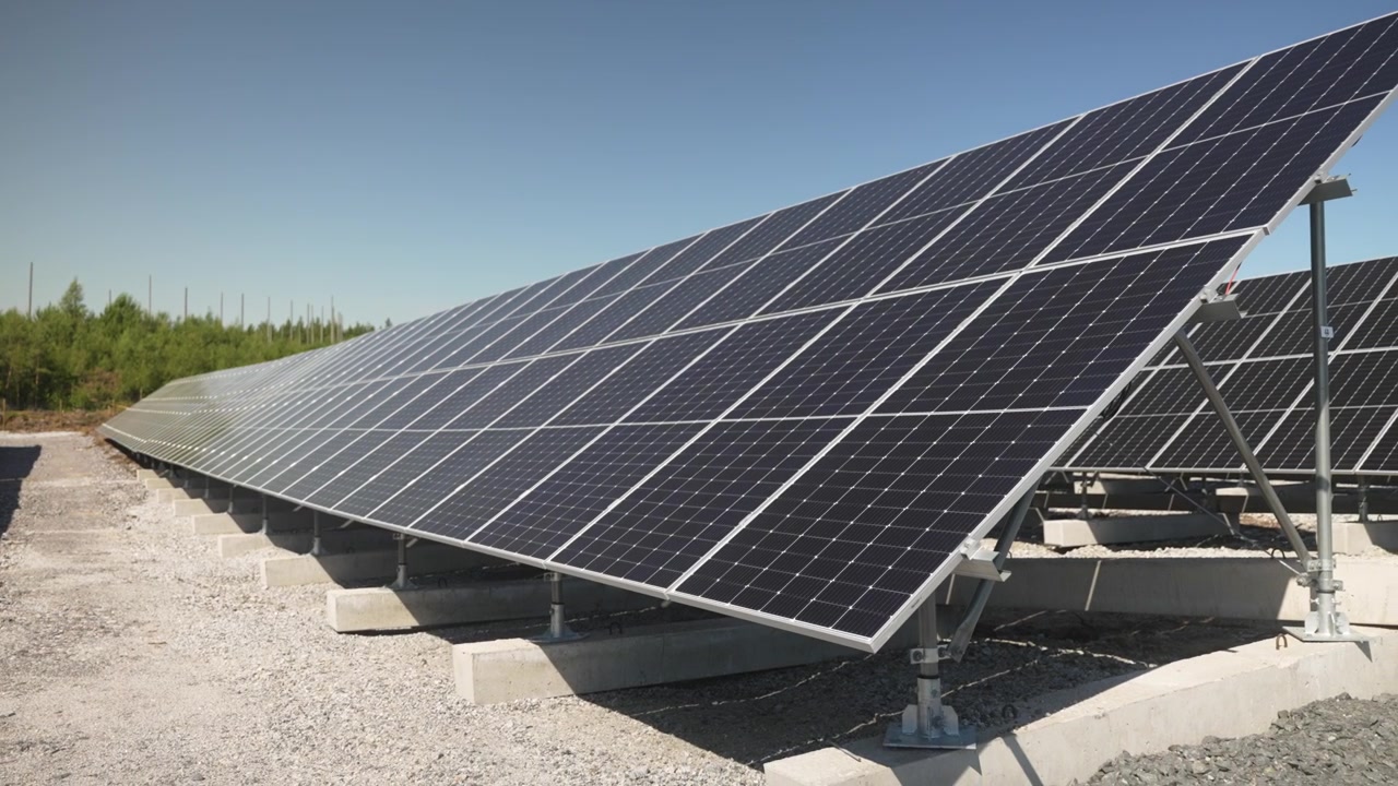 Ripresa angolata laterale in allontanamento lungo i pannelli solari che catturano la luce del sole in un impianto fotovoltaico, produzione di energia pulita e rinnovabile.