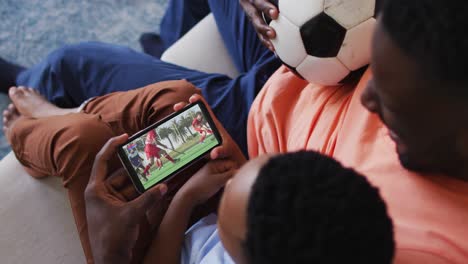 Compuesto-De-Padre-E-Hijo-En-Casa-Viendo-Un-Partido-De-Hockey-En-Un-Teléfono-Inteligente