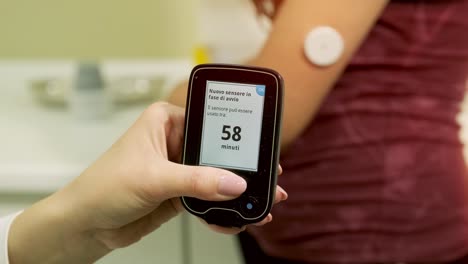 médico con una bomba de insulina conectada en el abdomen del paciente y sosteniendo la bomba de insulina en sus manos. concepto de diabetes.