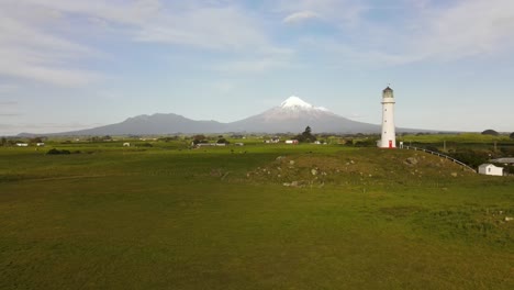 beautiful birds eye view of lighthouse, rural farmland and volcano with snowy top