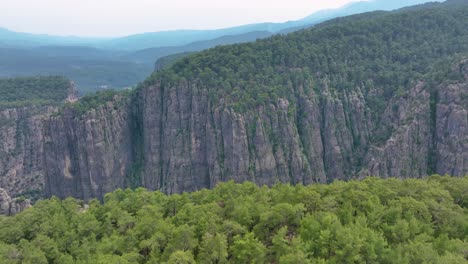 aerial view of a mountain valley with steep cliffs and forests