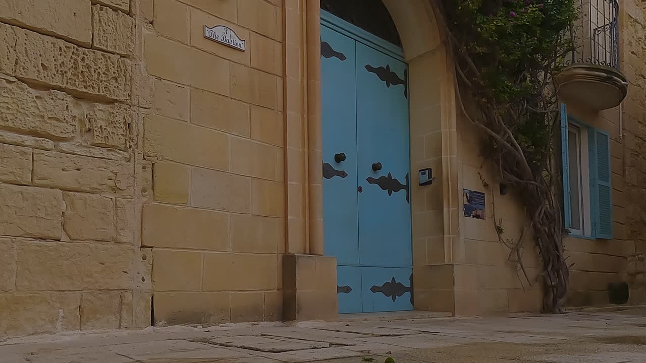 Malta'nın Mdina şehrindeki tarihi kumtaşı duvarda büyük mavi ahşap kapı.