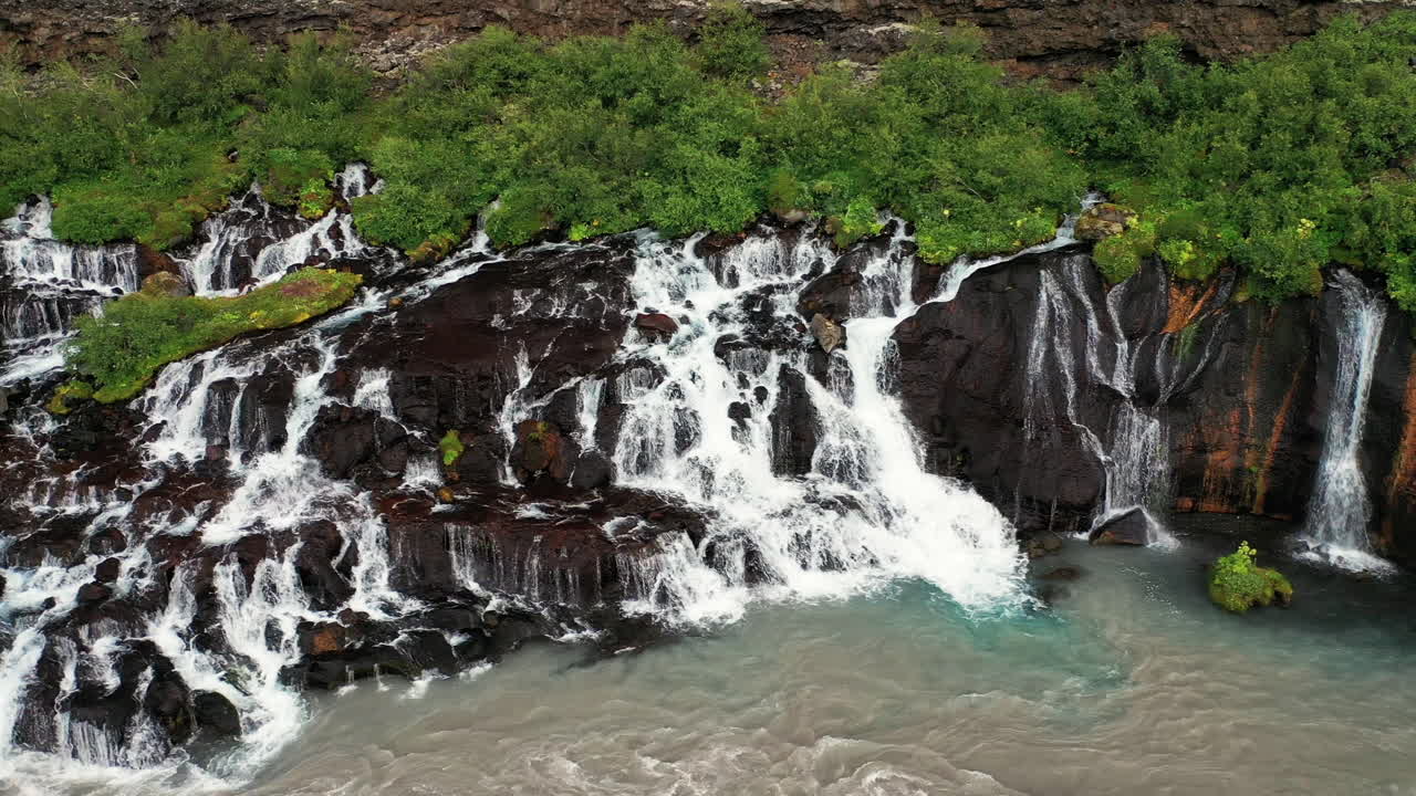 cascadas hraunfossar en cascada a hvita desde repisas de rocas cubiertas de musgo en el oeste de islandia