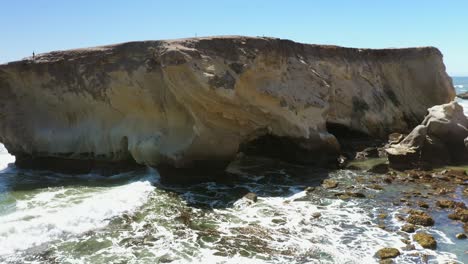 con el tiempo, las olas golpean contra un acantilado rocoso y crean un agujero que forma un arco en la piedra