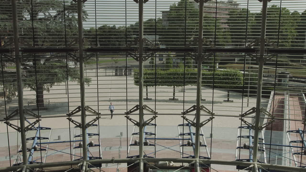 Handsomely dressed man goes to work in a large glass office businessman ode returns to the office