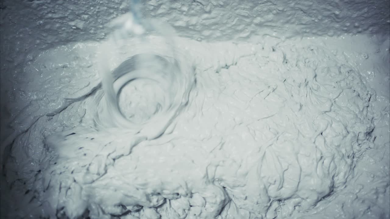 A Close-Up View of Mixing a Thick, Creamy Substance: Observing the Swirling Motion as Water Blends with a White Mixture to Create a Homogeneous Texture