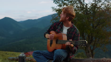 romantic millennial sing nature in mountains. smiling guy relax on travel camp.