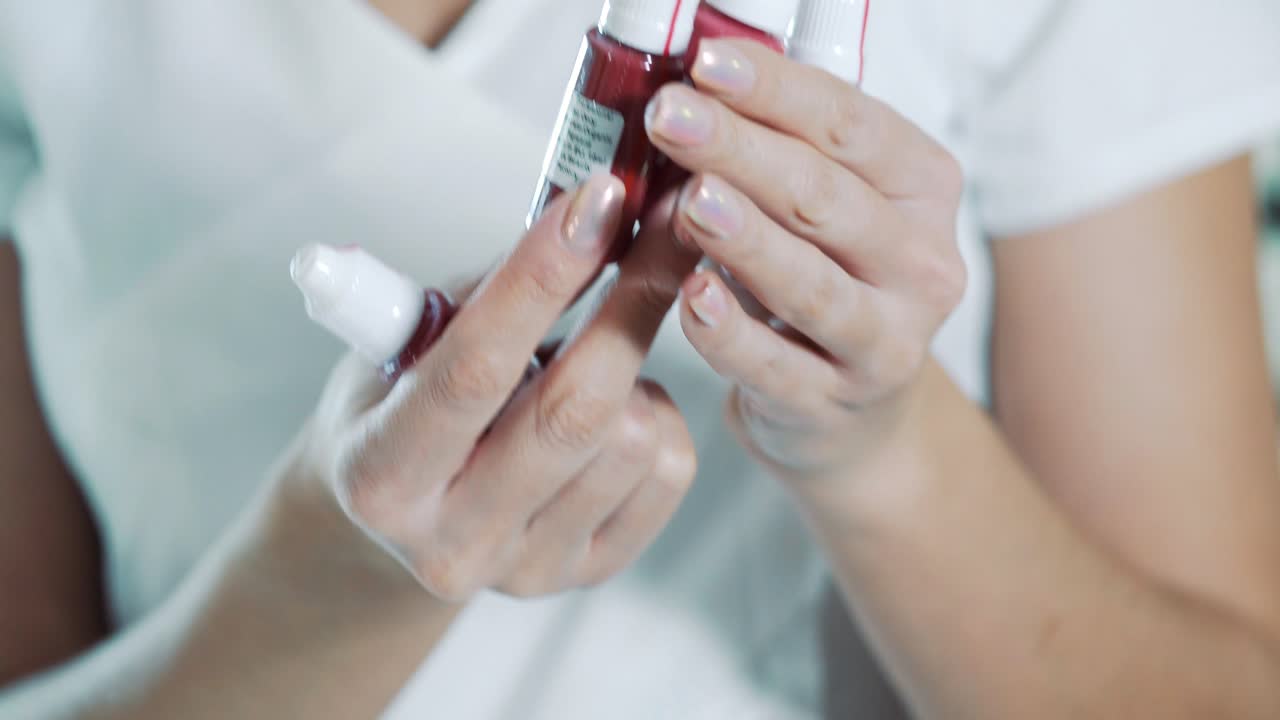 Female hands hold cosmetic bottles with permanent makeup paint. Production of cosmetics