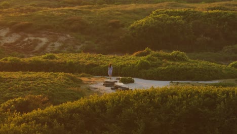 woman walking through a sandy landscape at sunset