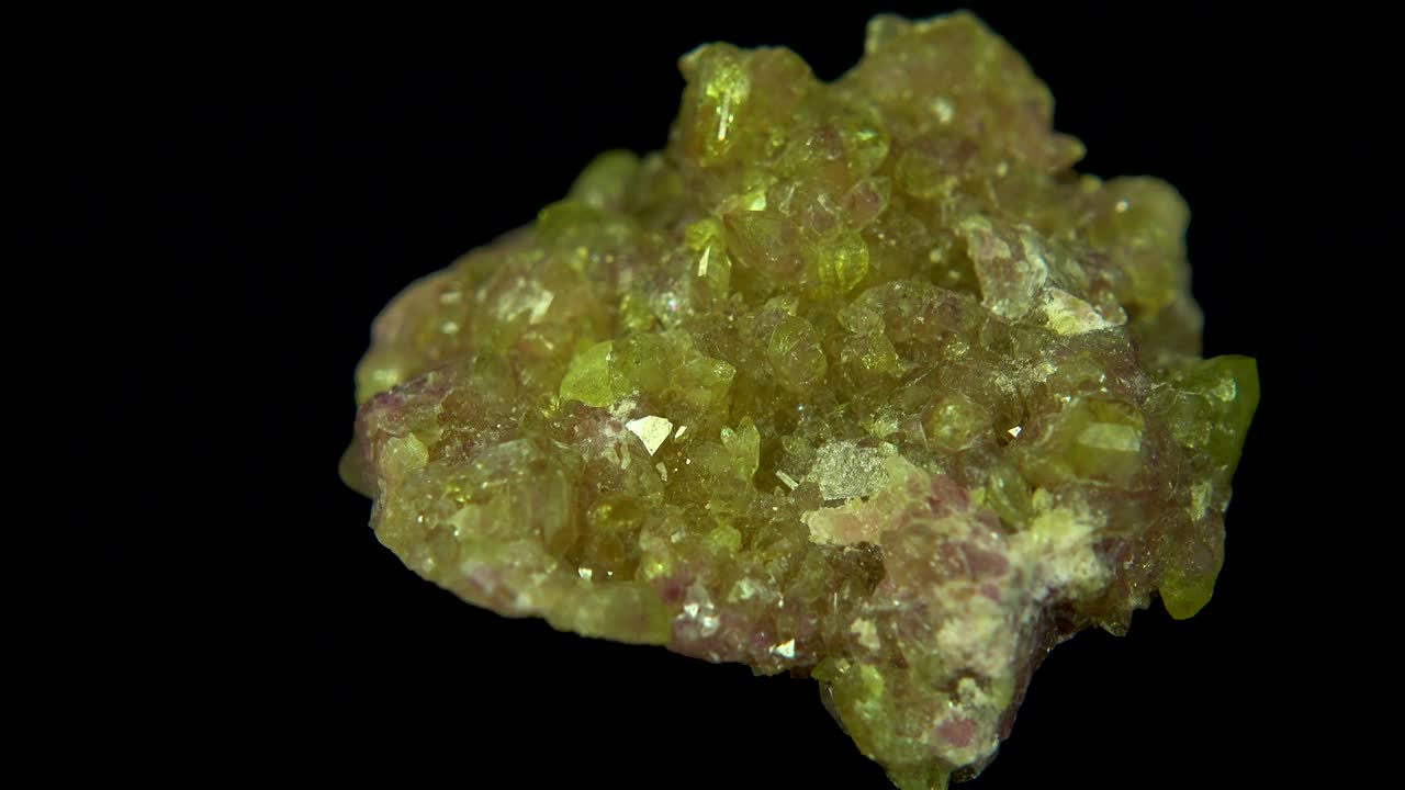 검은색 배경 앞에 라임 분홍색 미네랄 (베수비안) 을 원활하게 회전시니다.